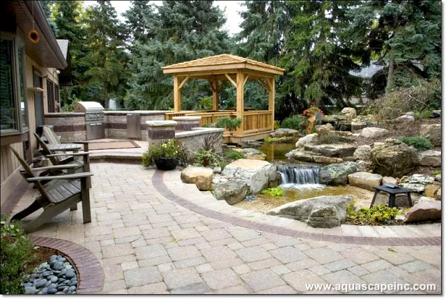 Outdoor kitchen to the left, beautiful paver patio for enjoying waterfront views, and a floating deck and gazebo for personal interaction with this amazing pond and waterfall.