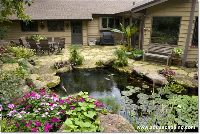 Flagstones create a natural-looking patio to complete this ecosystem pond. Note the large windows for indoor viewing!