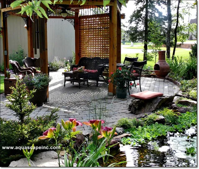 French-style patio furniture fits snugly under a pergola for pondside enjoyment.