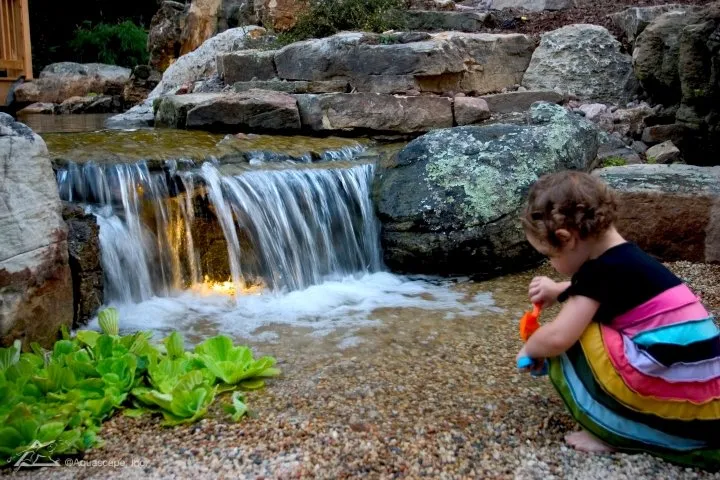 child playing near pondless waterfall