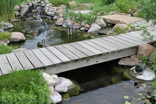 A rustic bridge leads straight from the back porch door, over the water garden, and out to the patio for pondside dining and entertainment.