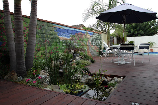 A magical water garden is tucked smack dab into the middle of the deck, carved out specifically for this tiny pond.