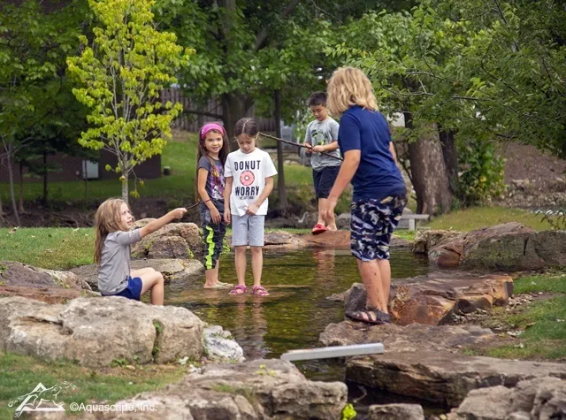 Kids Exploring Aquascape Waterfall at Park