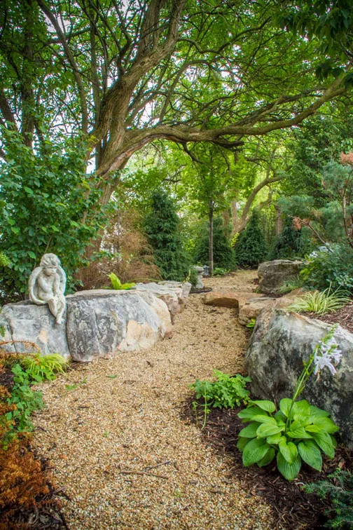 A simple stone path winds its way throughout the landscape, revealing plants and water features at every bend ...