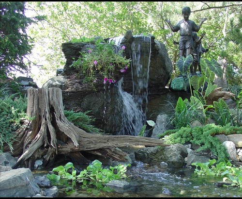 Unique use of rock, log, and statues in a backyard pond and waterfall by New Jersey Pond Contractor BJL Aquascapes