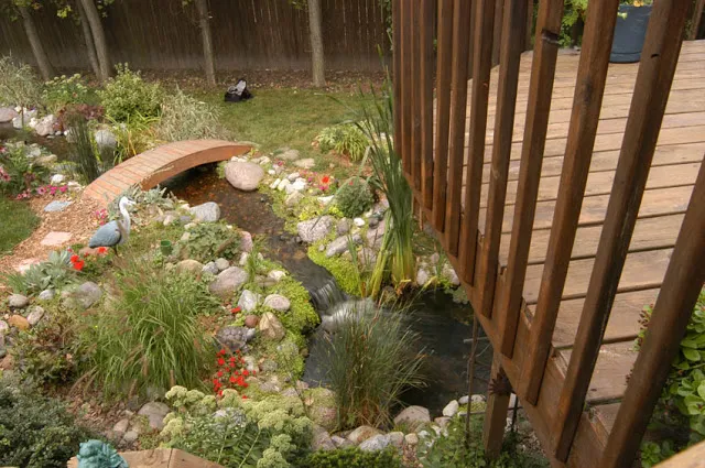 The owners of this deck enjoy a view of a meandering stream that spills into a pond by their lower level patio.